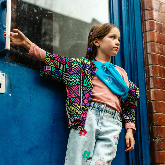 A young girl wearing a stylish blue crossbody bum bag, perfect for kids, with a compact and trendy design for easy carrying essentials.