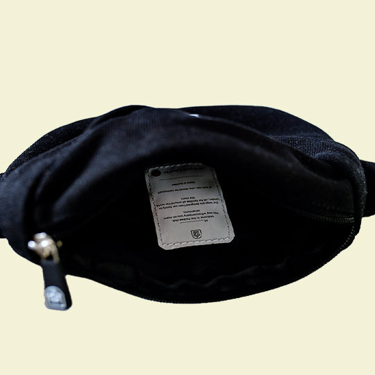Kids black bum bag with an open main compartment, spacious interior, and a name and contact detail tag with Pachee welcome note.