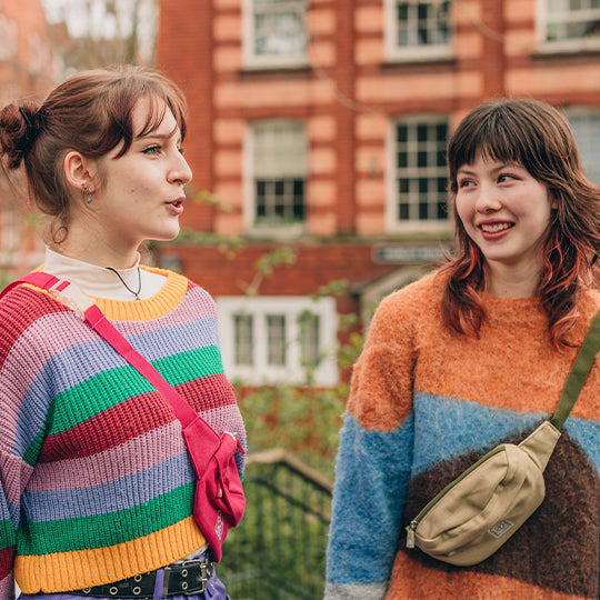 Two girls wearing stylish cross-body bum bags; one in pink, the other in neutral, showcasing stylish, hands-free convenience.