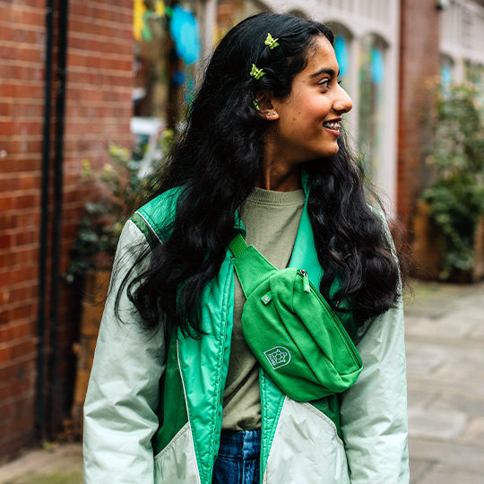 A young Girl wearing a stylish green crossbody bumbag over her shoulder, perfect for casual outings and everyday essentials.