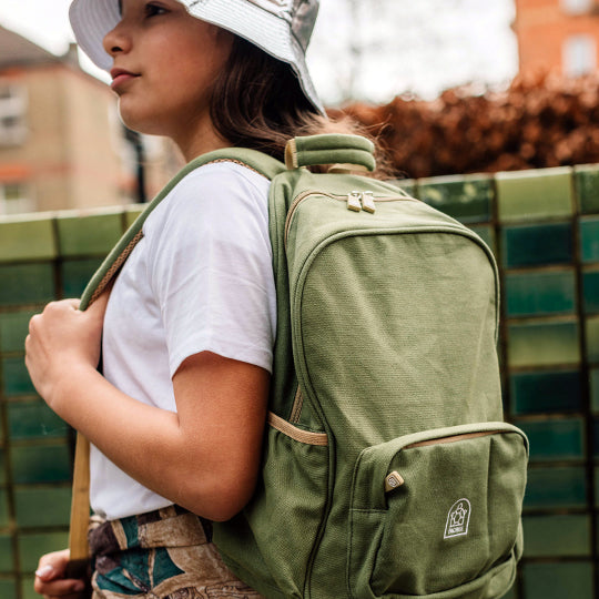Young girl wearing a sage green school backpack, showcasing a stylish and practical choice for kids' back-to-school gear.