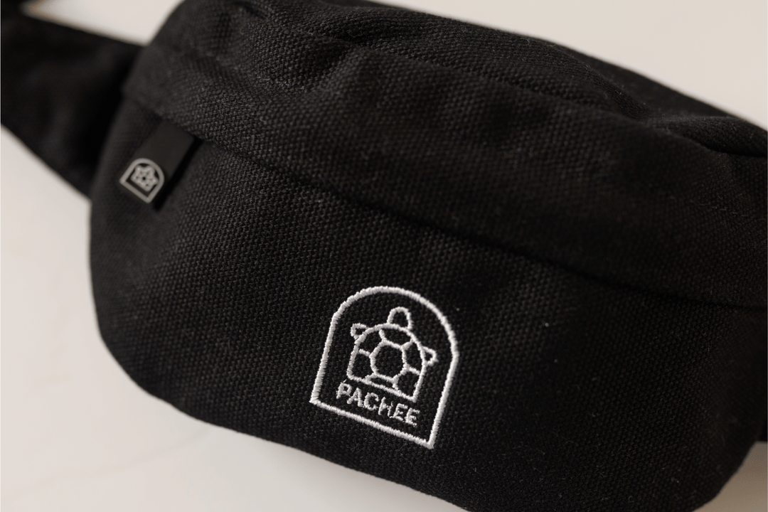 A front view of sleek black bum bags featuring the Pachee logo in the center, showcasing a minimalist and stylish design for casual wear.
