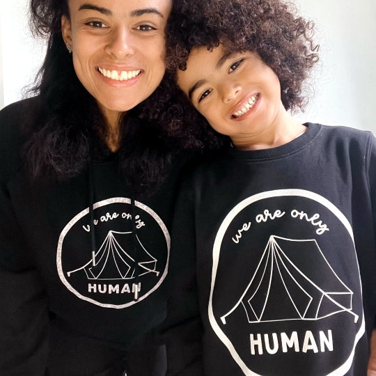 Boy wearing Kids Black Statement Sweatshirt and woman in Black Statement Hoody, both featuring the "We Are Only Human" slogan.