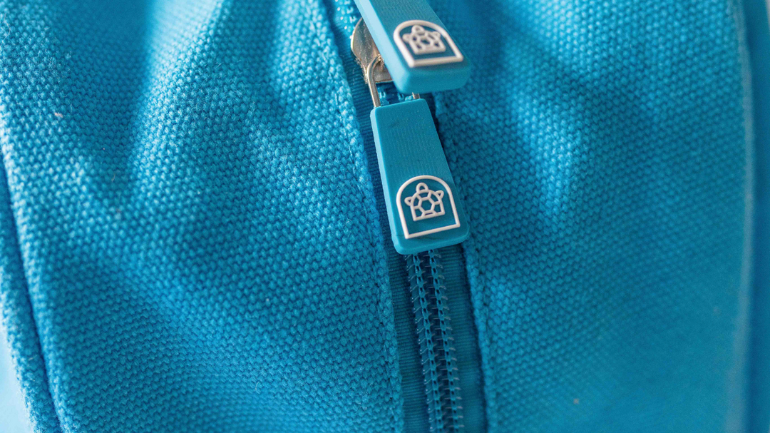  Blue backpack featuring a closed zipper with the Pachee logo prominently displayed on it.