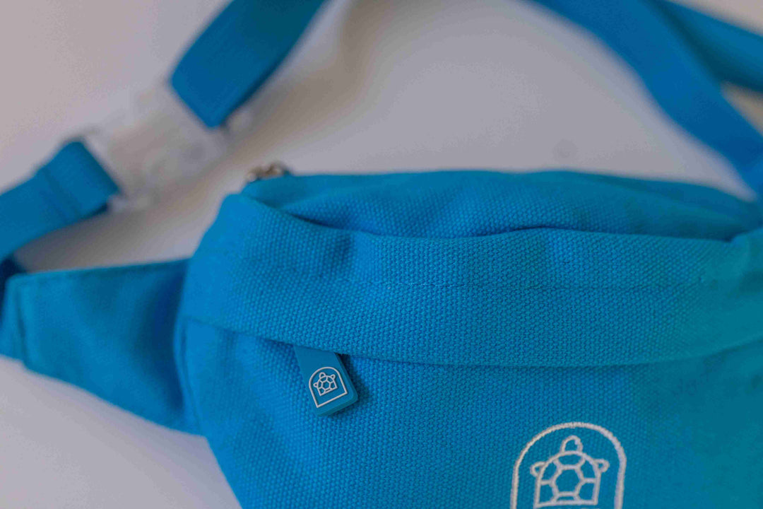 Close-up of a blue bum bag featuring a high-quality front zip with detailed stitching and a visible Pachee logo.
