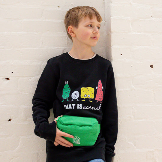 Young boy wearing a black organic cotton sweatshirt with the "What is Normal" statement, stylish and comfortable.