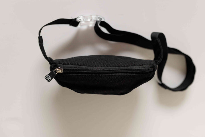 A black canvas zipper bum bag viewed from the top, showcasing the closed zipper and adjustable straps laid flat for a clear top view.