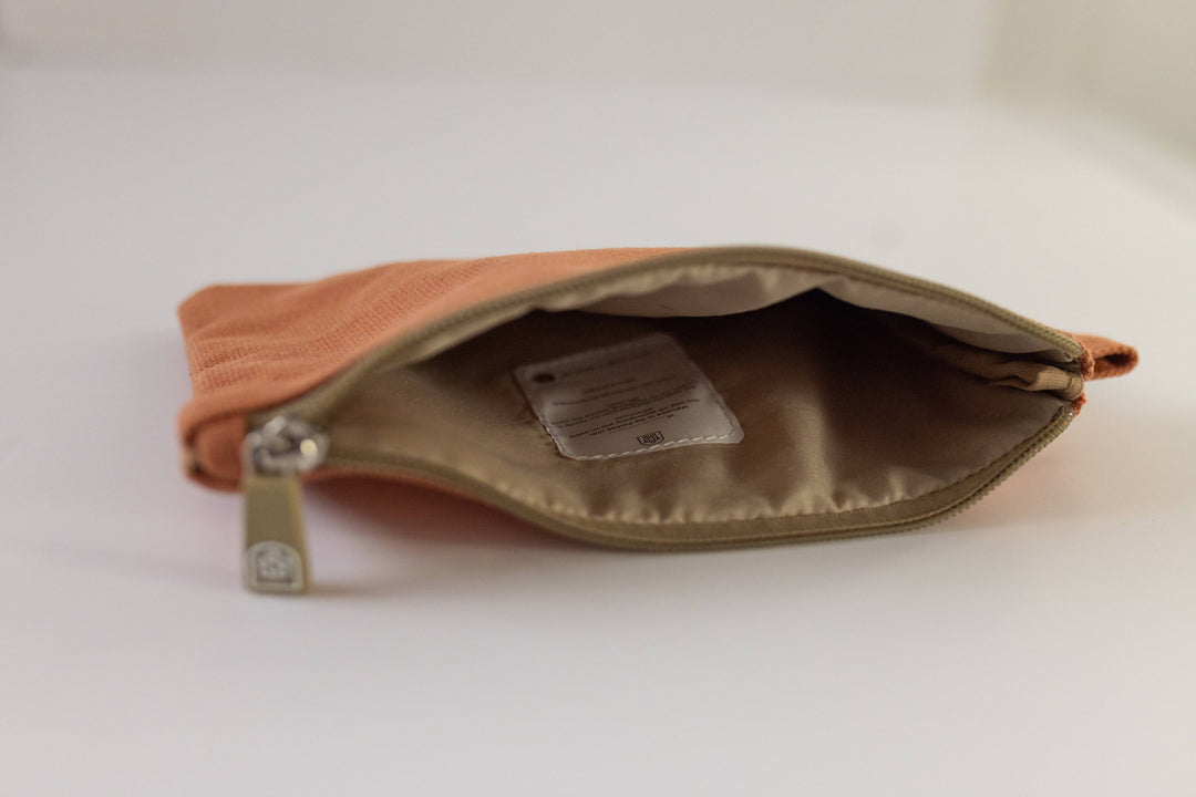 An open orange canvas zipper pouch displayed on a surface, showcasing its interior. Available at Pachee, UK online store.