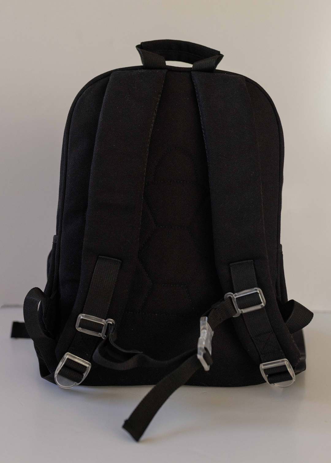 Black Junior backpack featuring adjustable back shoulder straps and a waist strap with a transparent buckle, available at Pachee.