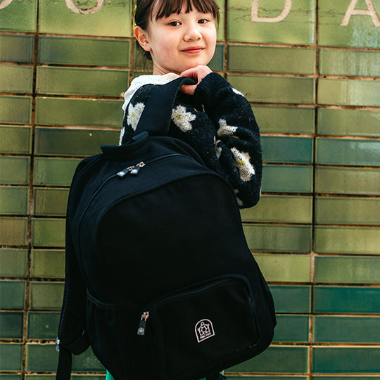 Young girl wearing a black junior backpack on her shoulder, perfect for kids' school or casual use.