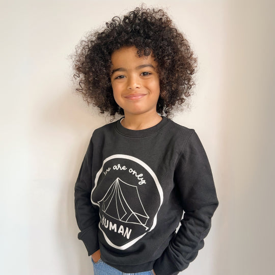 Boy wearing a Kids Black Statement Sweatshirt with the slogan "We Are Only Human" in bold white text. Available at Pachee. 
