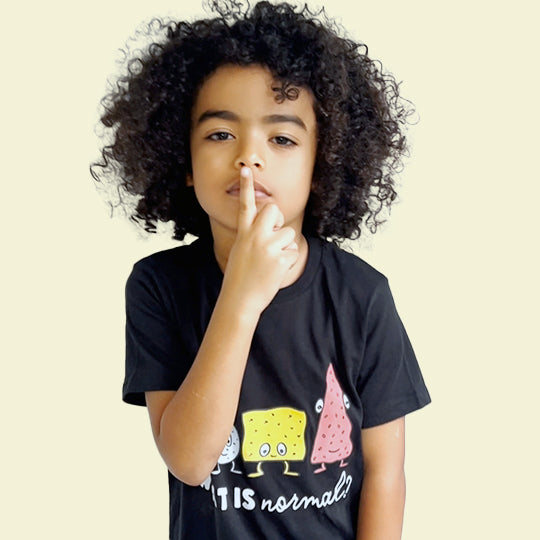 Boy wearing an organic cotton black T-shirt with the statement "WHAT IS normal?" in white font and funny faces