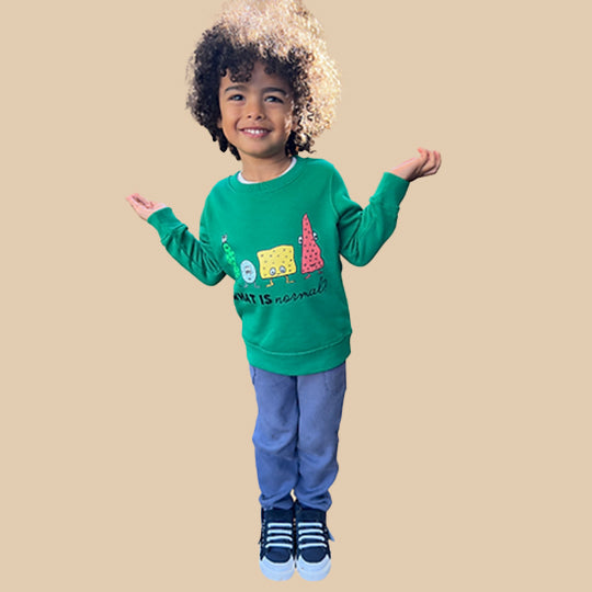 Young boy wearing a green kids sweatshirt with 'What is normal?' statement and funny faces printed on it.