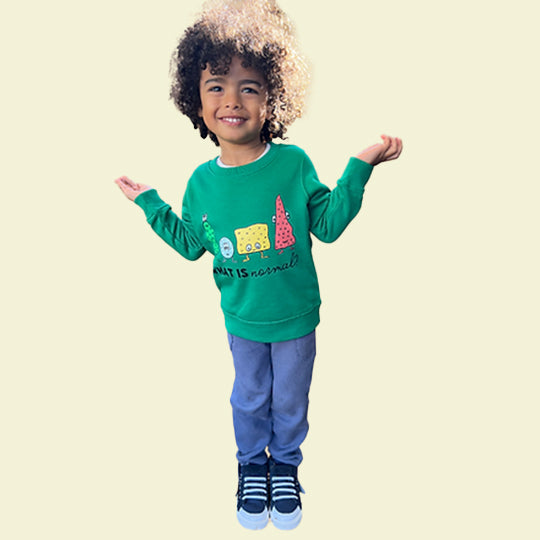 Young boy wearing a green kids sweatshirt with 'What is normal?' statement and funny faces printed on it.