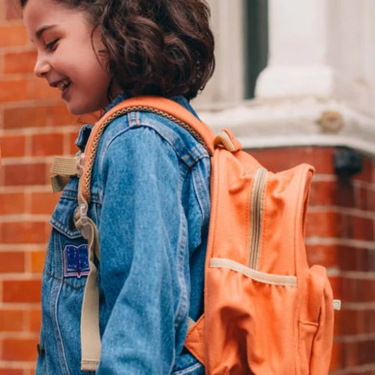 Girl wearing an orange mini backpack from Pachee, showcasing a stylish and fun design for kids school use.