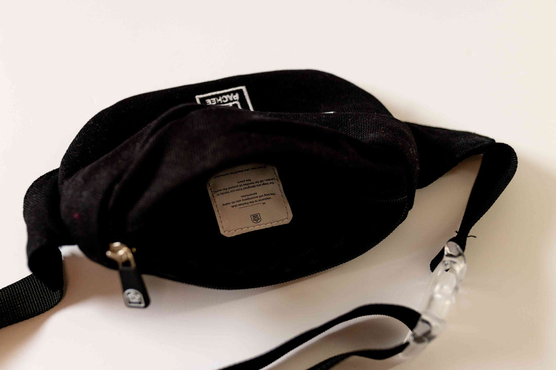 Black bum bag with the main compartment opened, revealing spacious interior, and a clear view of the transparent buckle on the strap.