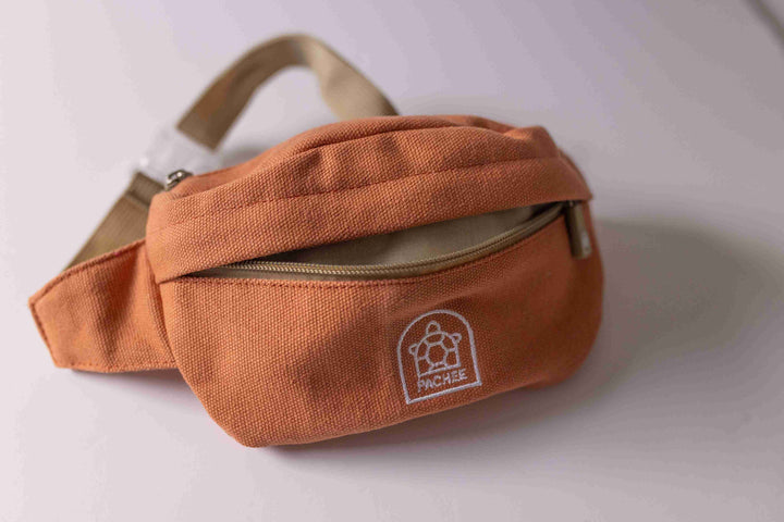 Kids trendy orange crossbody bum bag with an opened front compartment, showcasing storage space. Available at Pachee.