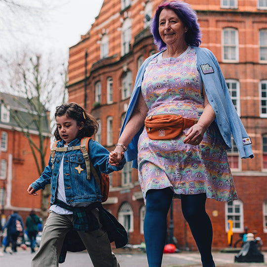 A woman wearing an orange waist bum bag, walking with child in a casual outdoor setting.