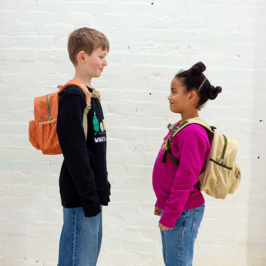 Boy wearing an orange personalised backpack and girl with a neutral colour backpack, available at Pachee online store.