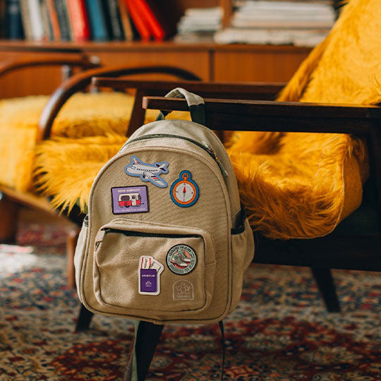 Mini backpack personalised with Travel-Club patches including Compass, Aeroplane, Passport, Climb, and Mini-nomad Campervan patches.