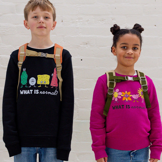 A young boy in a black sweatshirt and a young girl in a pink sweatshirt, both with the "What is normal" statement on them.